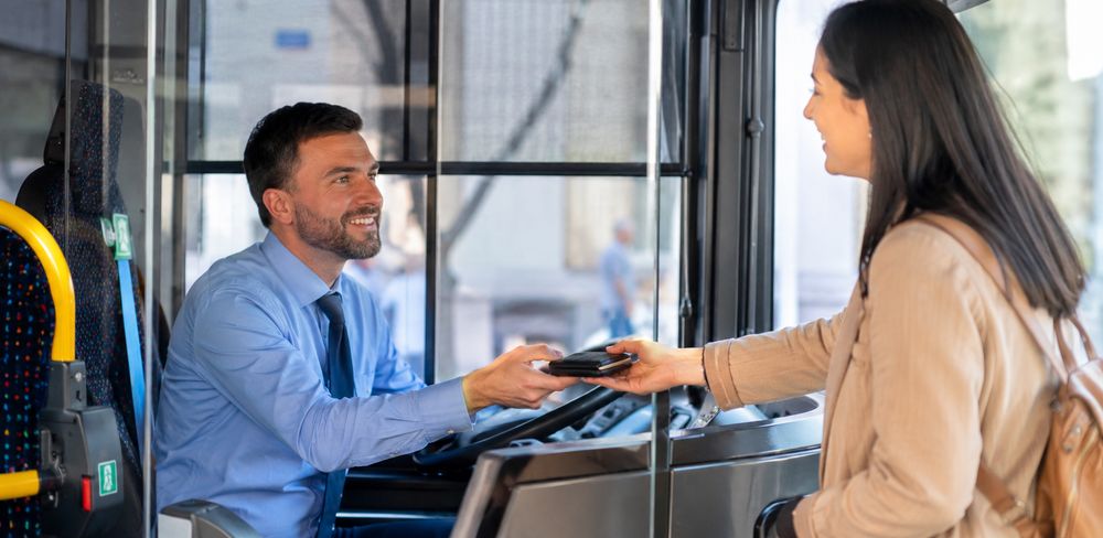 Un conductor de autobús entrega una cartera a una pasajera.
